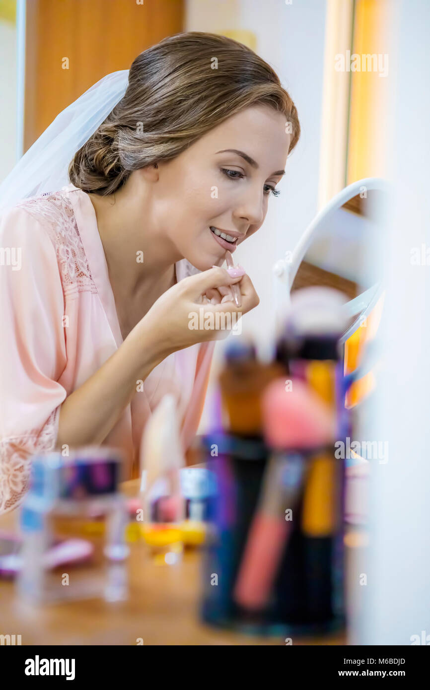 Giovane bella sposa applicazione wedding make up. Focus sulle labbra! Foto Stock