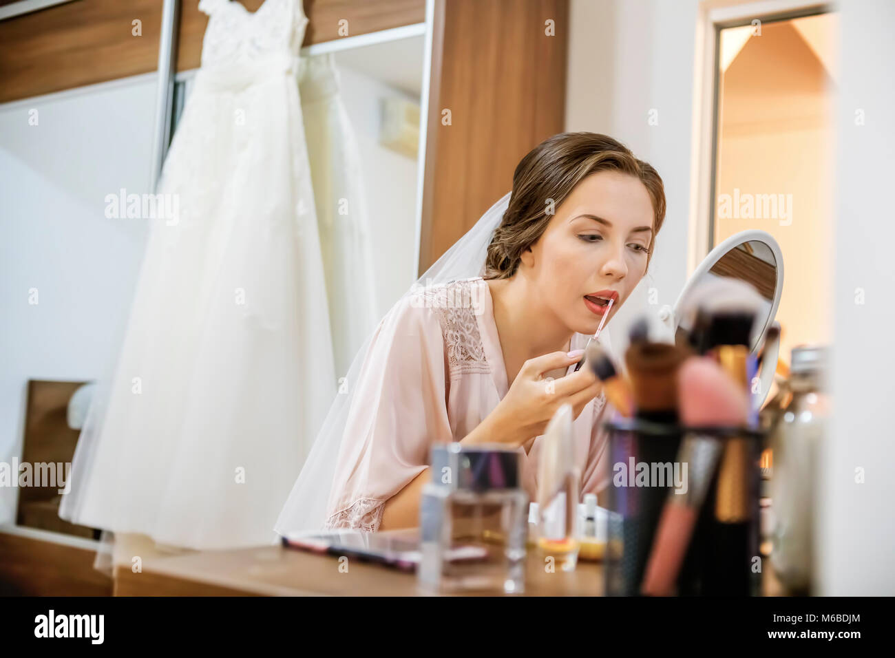 Trucco rossetto sulla sposa le labbra con la spazzola. Focus sulle labbra! Foto Stock