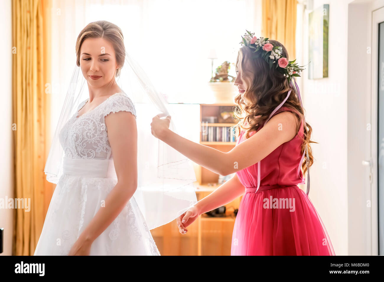 Aiutare la sposa a mettere il suo abito da sposa a Foto Stock