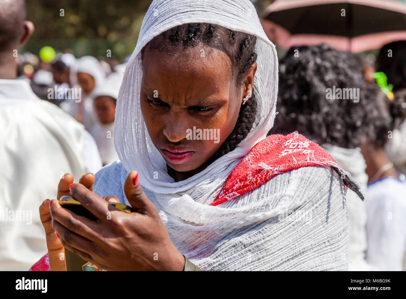 Una donna etiope guardando con preoccupazione per il suo telefono cellulare, Addis Abeba, Etiopia Foto Stock