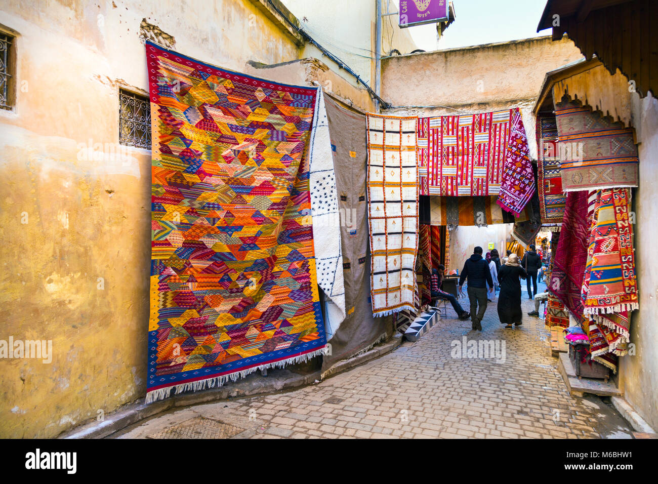 Una strada stretta nel souk della medina con tappeto marocchino negozi, Fes, Marocco Foto Stock