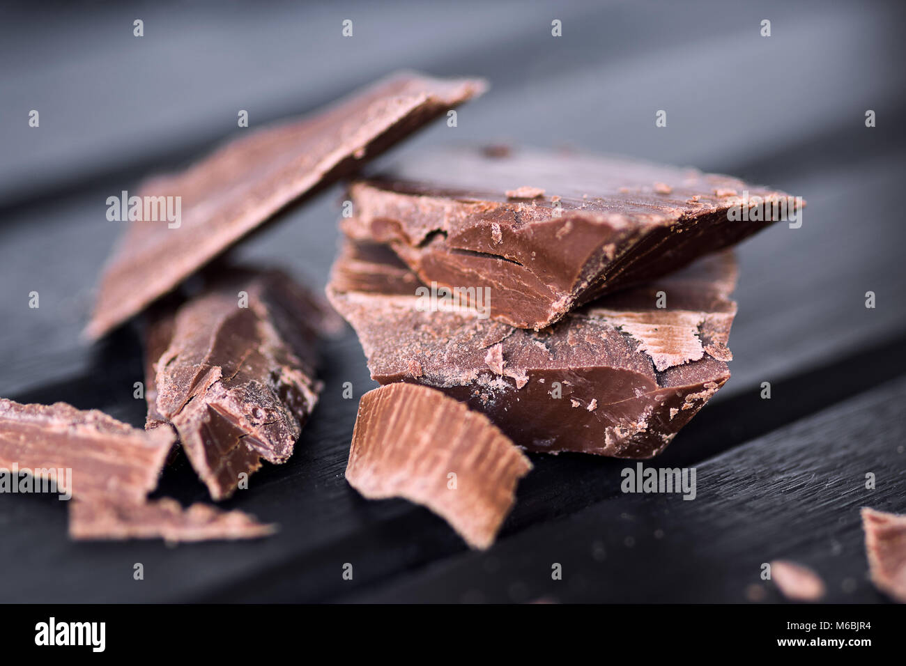 Deliziosi pezzetti di cioccolato su un legno scuro dello sfondo moody, closeup macro, con un sacco di texture Foto Stock