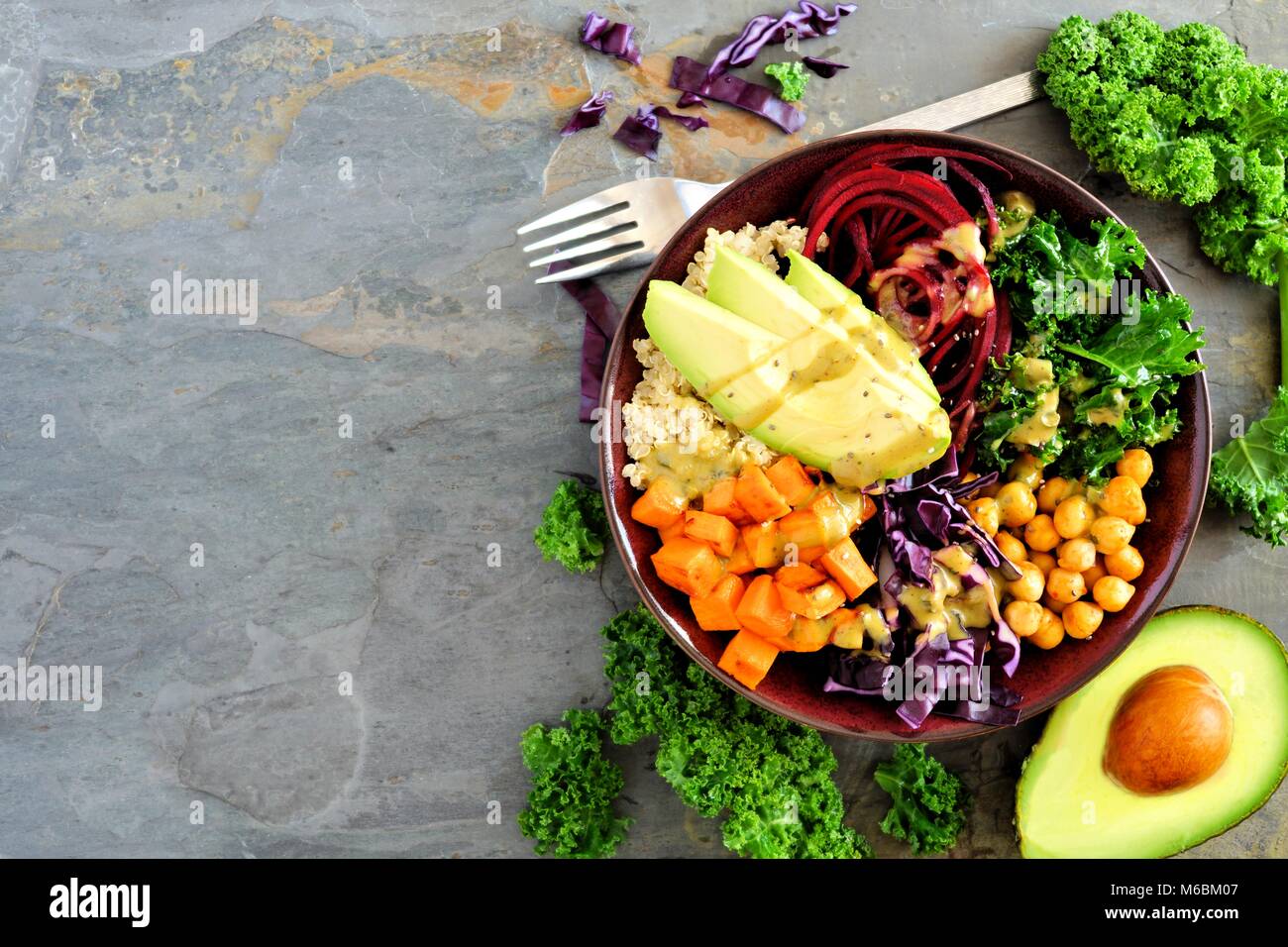 Ciotola di Buddha con la quinoa, avocado, ceci, verdure su uno sfondo scuro, cibo sano concetto. Vista dall'alto, bordo laterale con copia spazio. Foto Stock