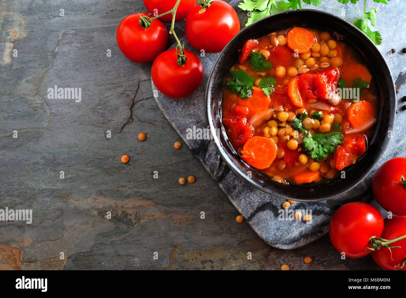 In casa di pomodoro, zuppa di lenticchie, sopra ad angolo vista confine con spazio copia al buio su un sfondo di ardesia Foto Stock