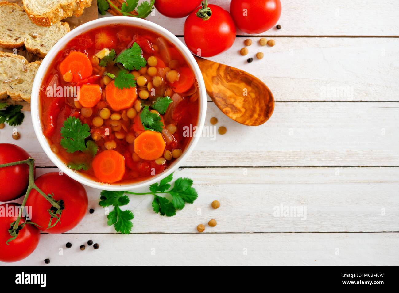 In casa di pomodoro, zuppa di lenticchie, sopra ad angolo vista confine con copia spazio su un bianco sullo sfondo di legno Foto Stock