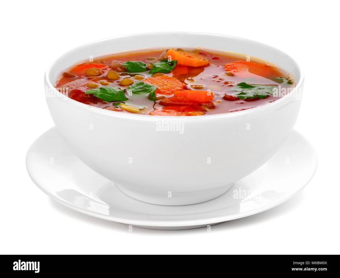 In casa di pomodoro, zuppa di lenticchie in un bianco ciotola con piattino. Vista laterale isolata su uno sfondo bianco. Foto Stock