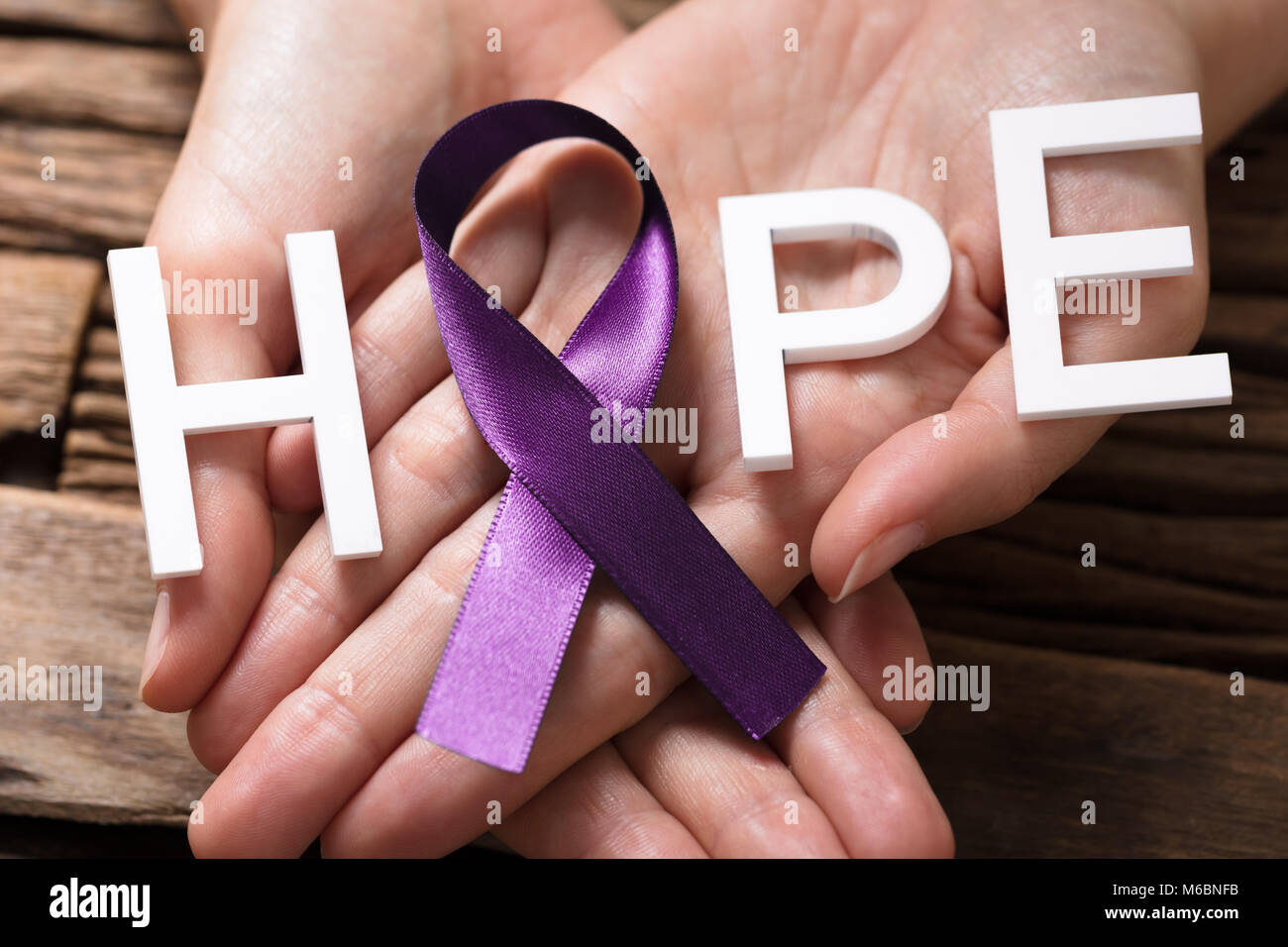 Close-up di mano di una persona che mostra il nastro con speranza il testo per supportare la malattia di Alzheimer la consapevolezza Foto Stock