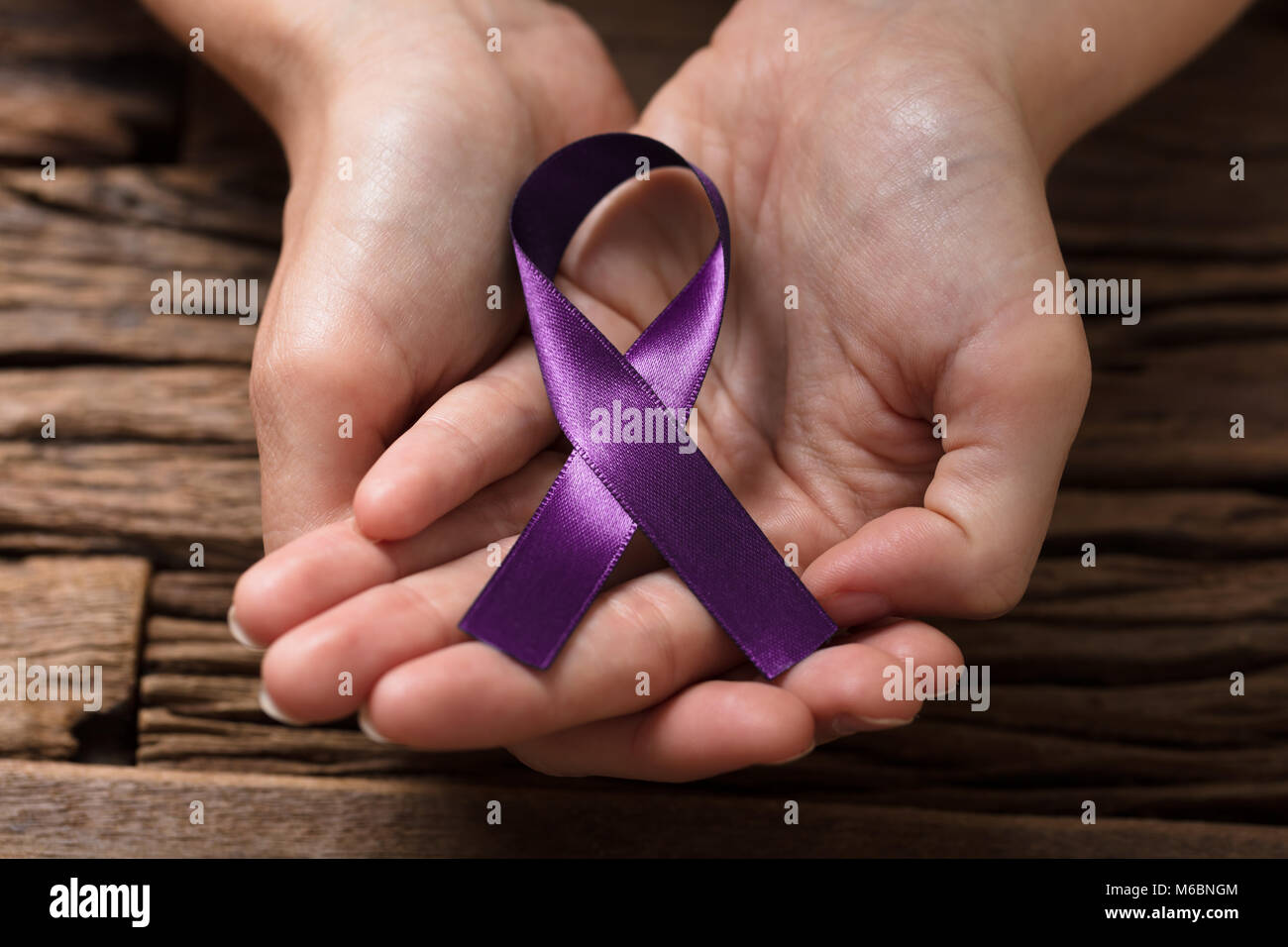 Close-up di una mano umana che mostra nastro viola per sostenere il cancro pancreatico consapevolezza Foto Stock