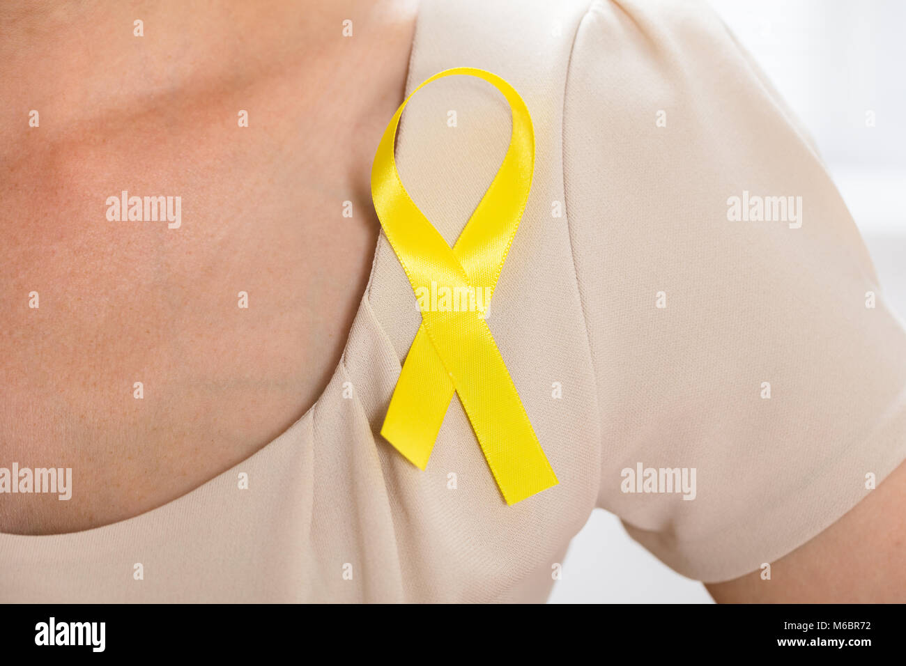 Close-up di una donna con nastro in oro per il supporto di infanzia e cancro della vescica Foto Stock