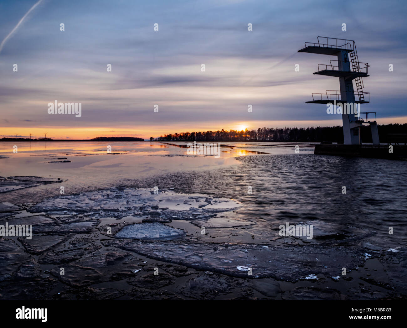 Torre di immersioni al tramonto in inverno con ghiaccio sul lago Foto Stock