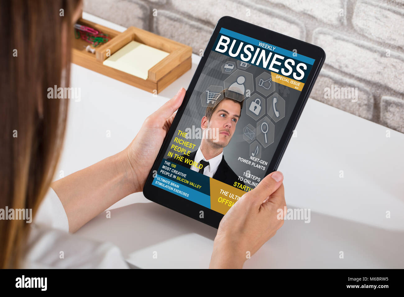 Una imprenditrice Guardando Business Magazine su tavoletta digitale sulla scrivania Foto Stock