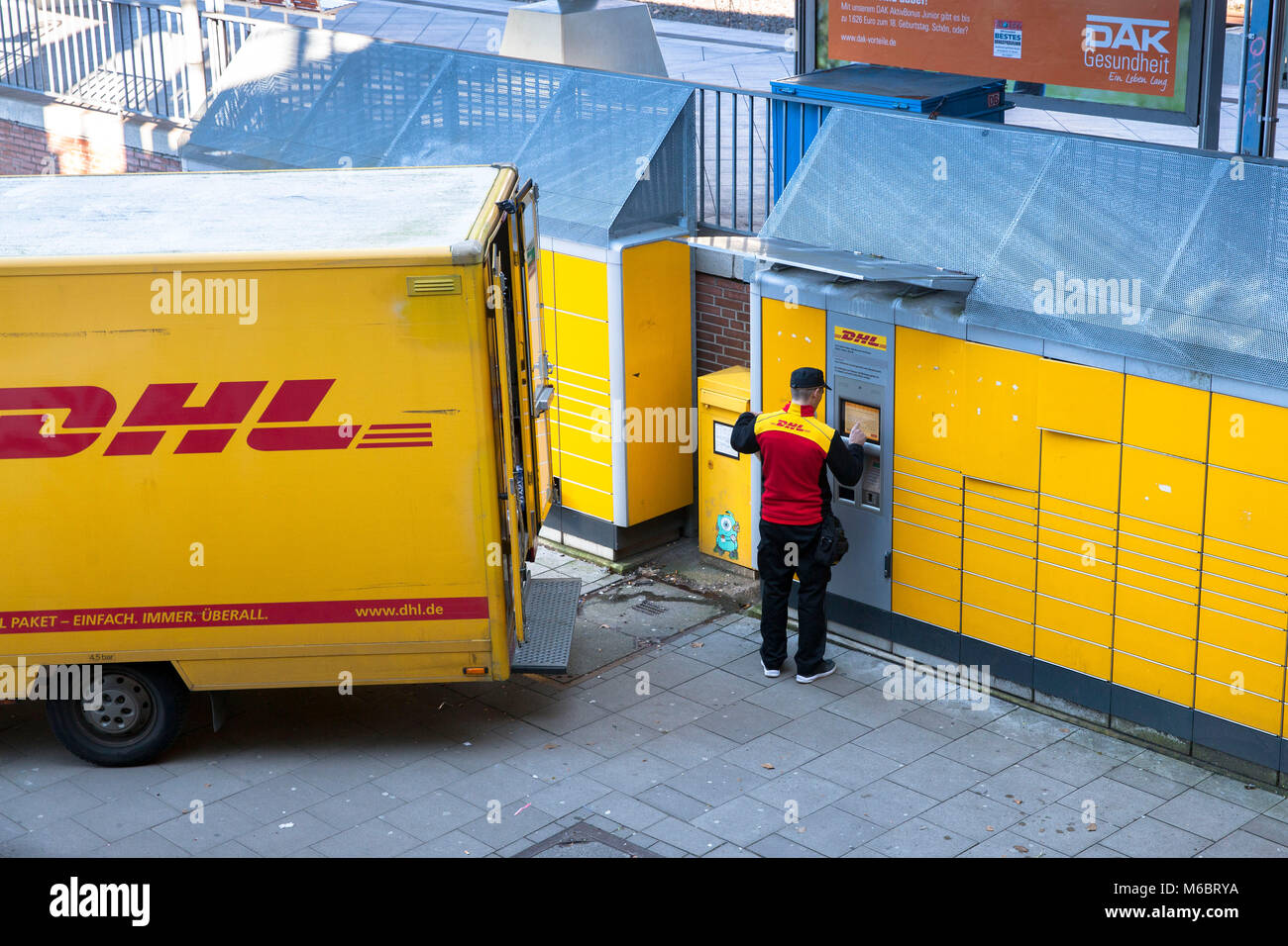 Germania, Colonia, un pacco DHL service driver fornisce un Packstation nel quartiere Deutz. Deutschland, Koeln, ein DHL beliefert Fahrer eine Packsta Foto Stock