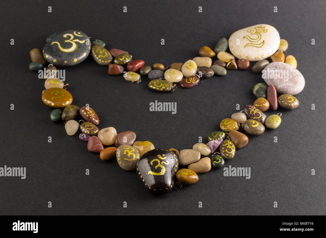 A forma di cuore ad mucchio di pietre dipinte con simbolo Om Foto Stock