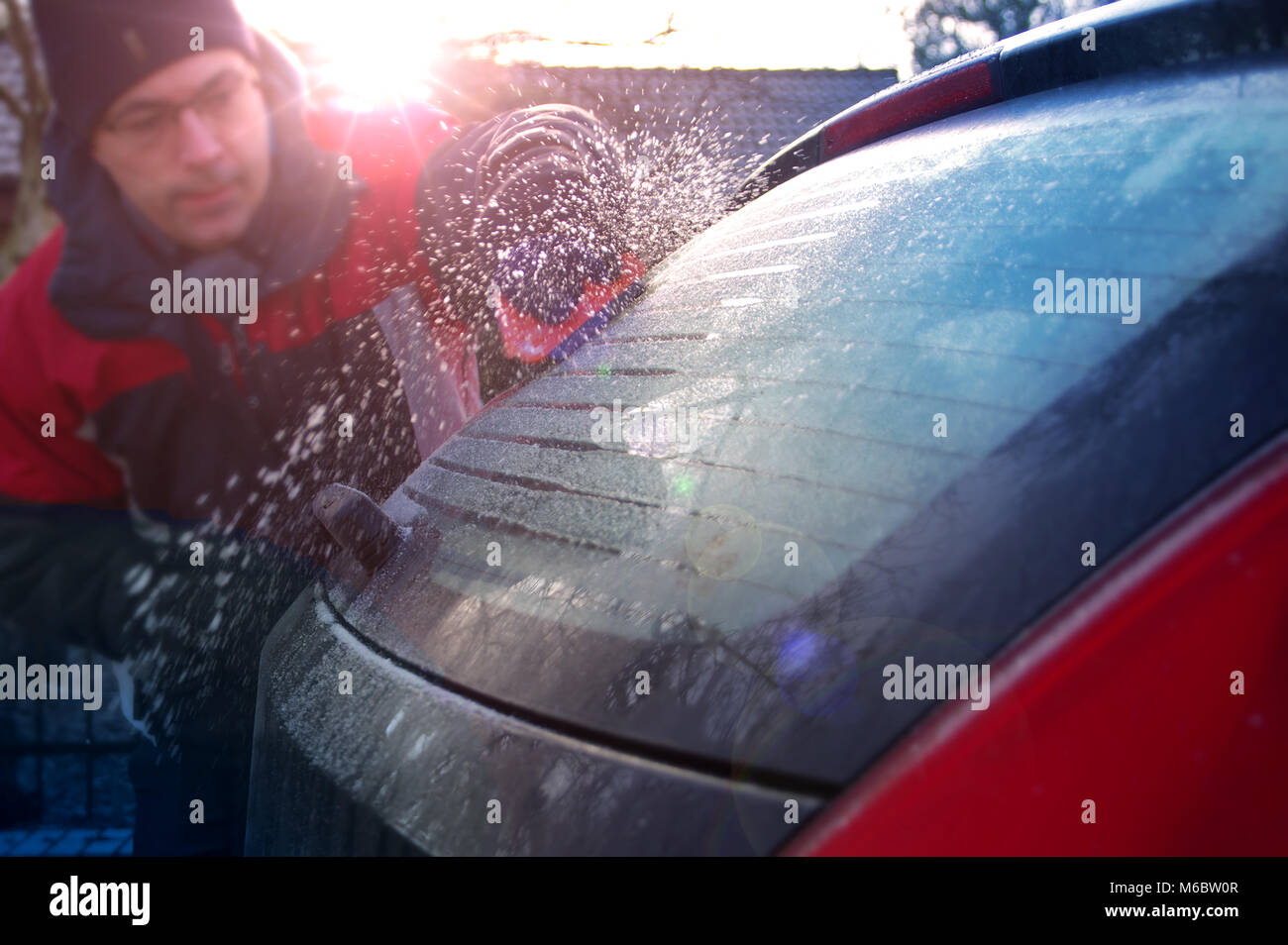 L'uomo la pulizia auto da neve e brina. Lo sbrinamento del veicolo nella stagione invernale. Foto Stock