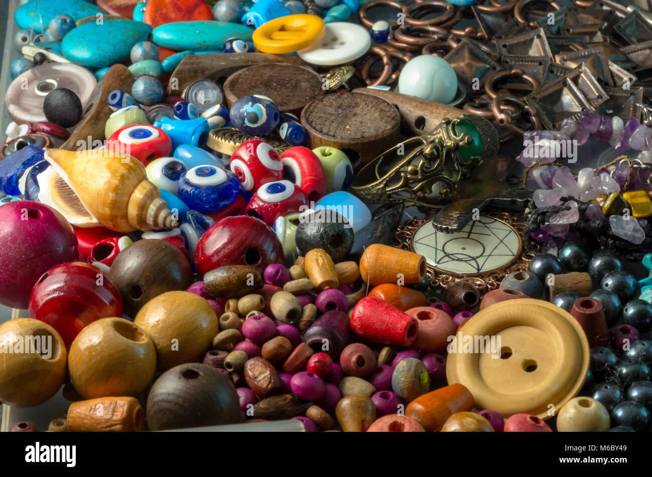 Pila di colorate perline di legno, pulsanti, perle, devil occhi e oggetti di metallo Foto Stock