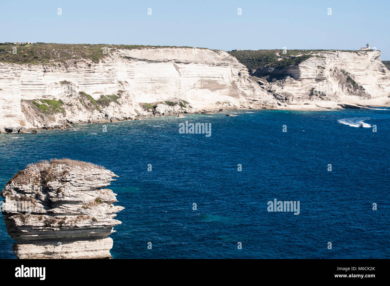 Corsica: la mozzafiato bianche scogliere calcaree nella International Bouches de Bonifacio parco marino con vista del capo Pertusato faro Foto Stock