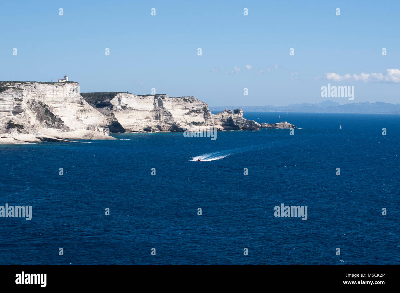 Corsica: la mozzafiato bianche scogliere calcaree nella International Bouches de Bonifacio parco marino con vista del capo Pertusato faro Foto Stock