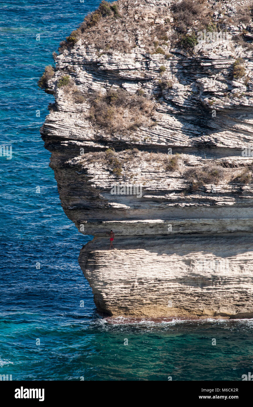 Corsica: l uomo è salito sul mozzafiato di pietra calcarea bianca scogliera di Bonifacio sulla punta meridionale dell'isola di fronte delle Bocche di Bonifacio Foto Stock