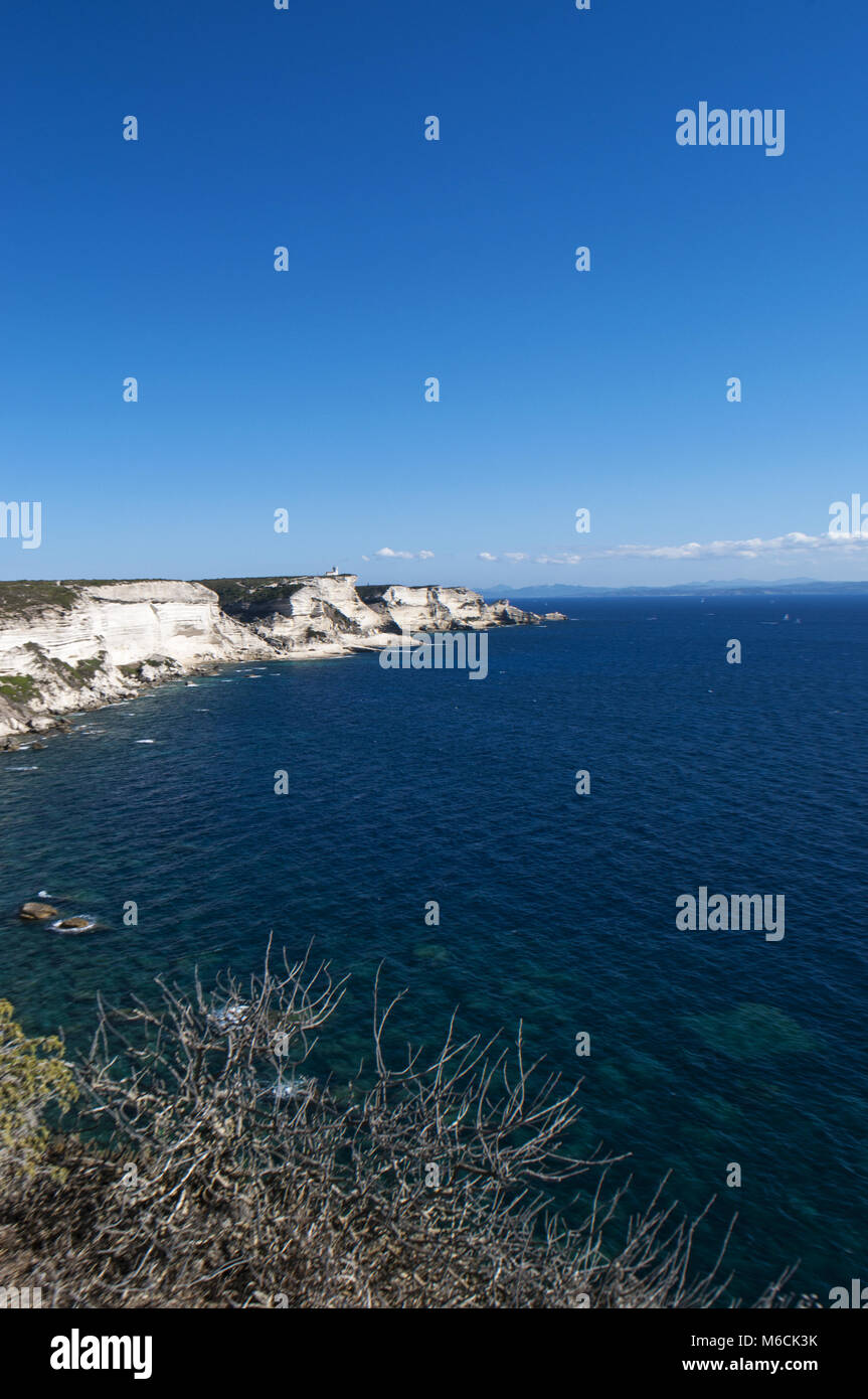 Corsica: la mozzafiato bianche scogliere calcaree nella International Bouches de Bonifacio parco marino con vista del capo Pertusato faro Foto Stock