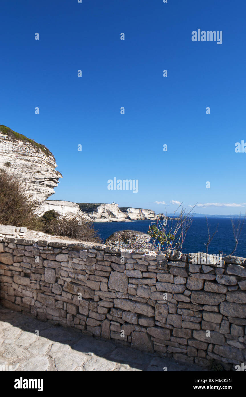 Corsica: muro di pietra e le bianche scogliere calcaree nella International Bouches de Bonifacio parco marino con vista del capo Pertusato faro Foto Stock