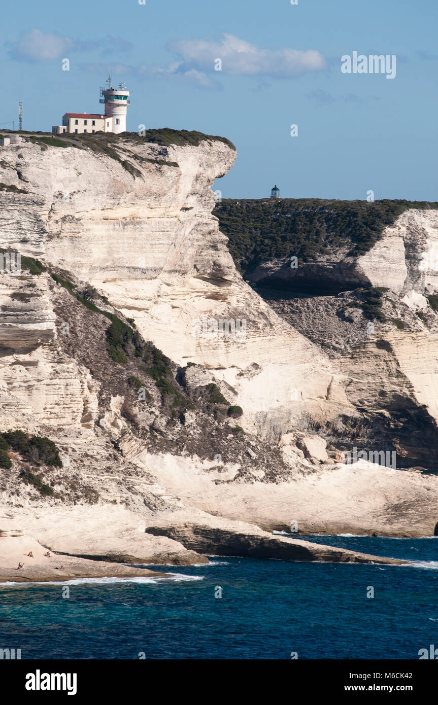 Corsica: la mozzafiato bianche scogliere calcaree nella International Bouches de Bonifacio parco marino con vista del capo Pertusato faro Foto Stock