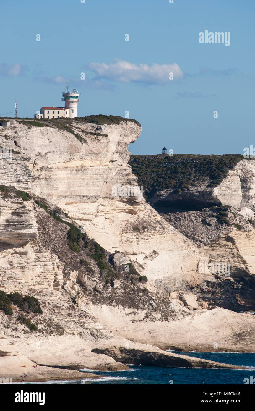 Corsica: la mozzafiato bianche scogliere calcaree nella International Bouches de Bonifacio parco marino con vista del capo Pertusato faro Foto Stock