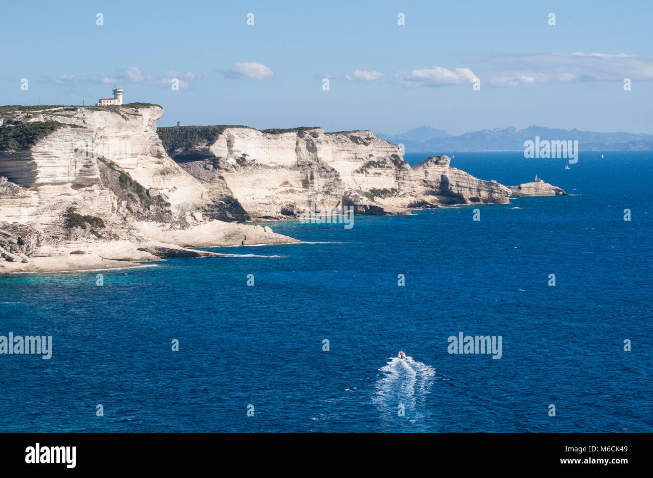 Corsica: la mozzafiato bianche scogliere calcaree nella International Bouches de Bonifacio parco marino con vista del capo Pertusato faro Foto Stock