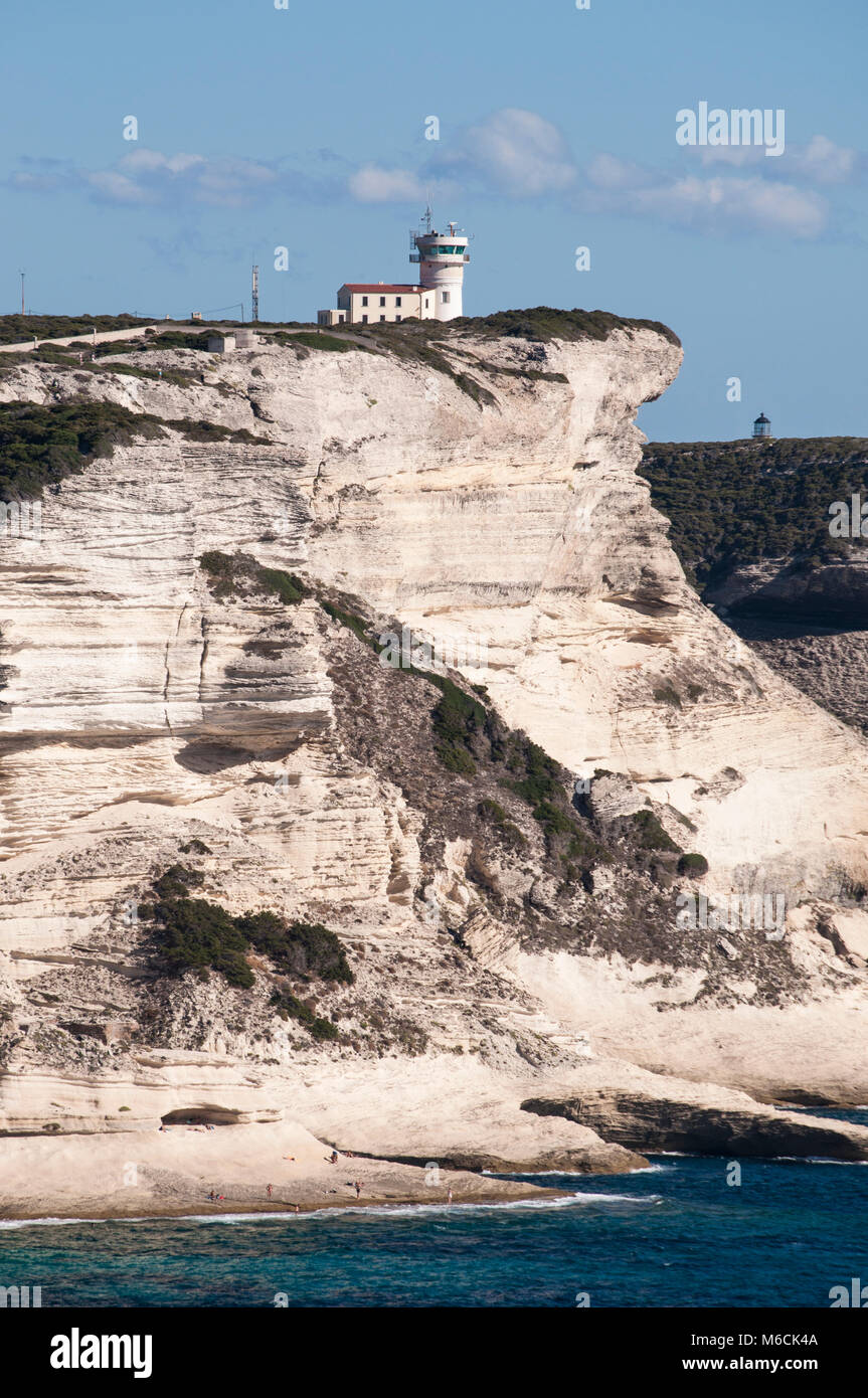 Corsica: la mozzafiato bianche scogliere calcaree nella International Bouches de Bonifacio parco marino con vista del capo Pertusato faro Foto Stock