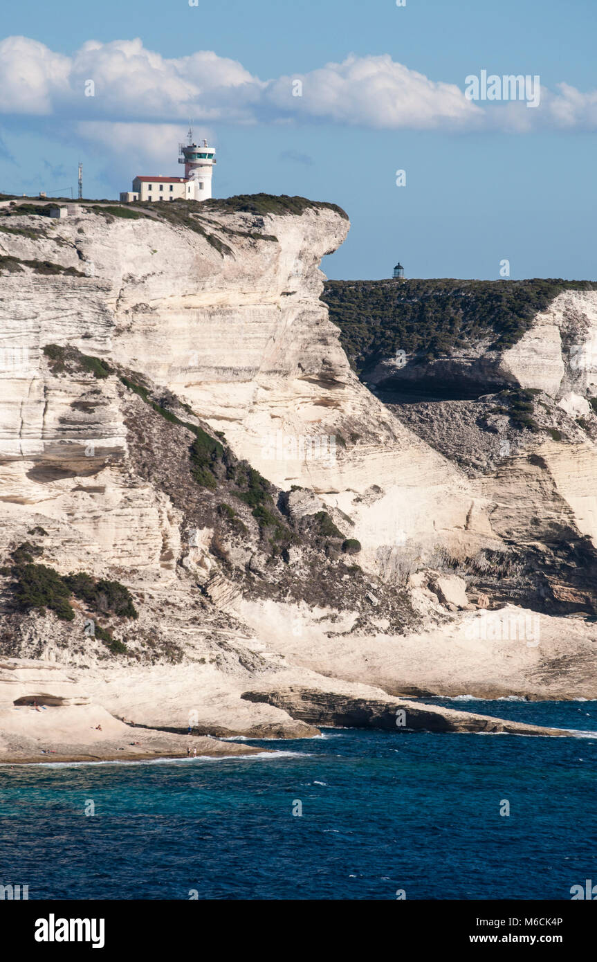 Corsica: la mozzafiato bianche scogliere calcaree nella International Bouches de Bonifacio parco marino con vista del capo Pertusato faro Foto Stock