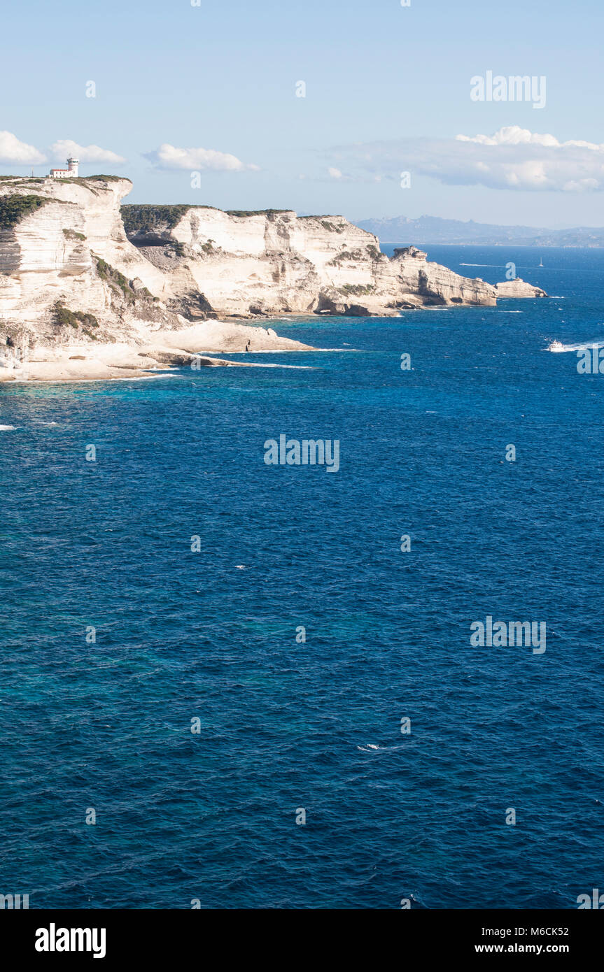 Corsica: la mozzafiato bianche scogliere calcaree nella International Bouches de Bonifacio parco marino con vista del capo Pertusato faro Foto Stock