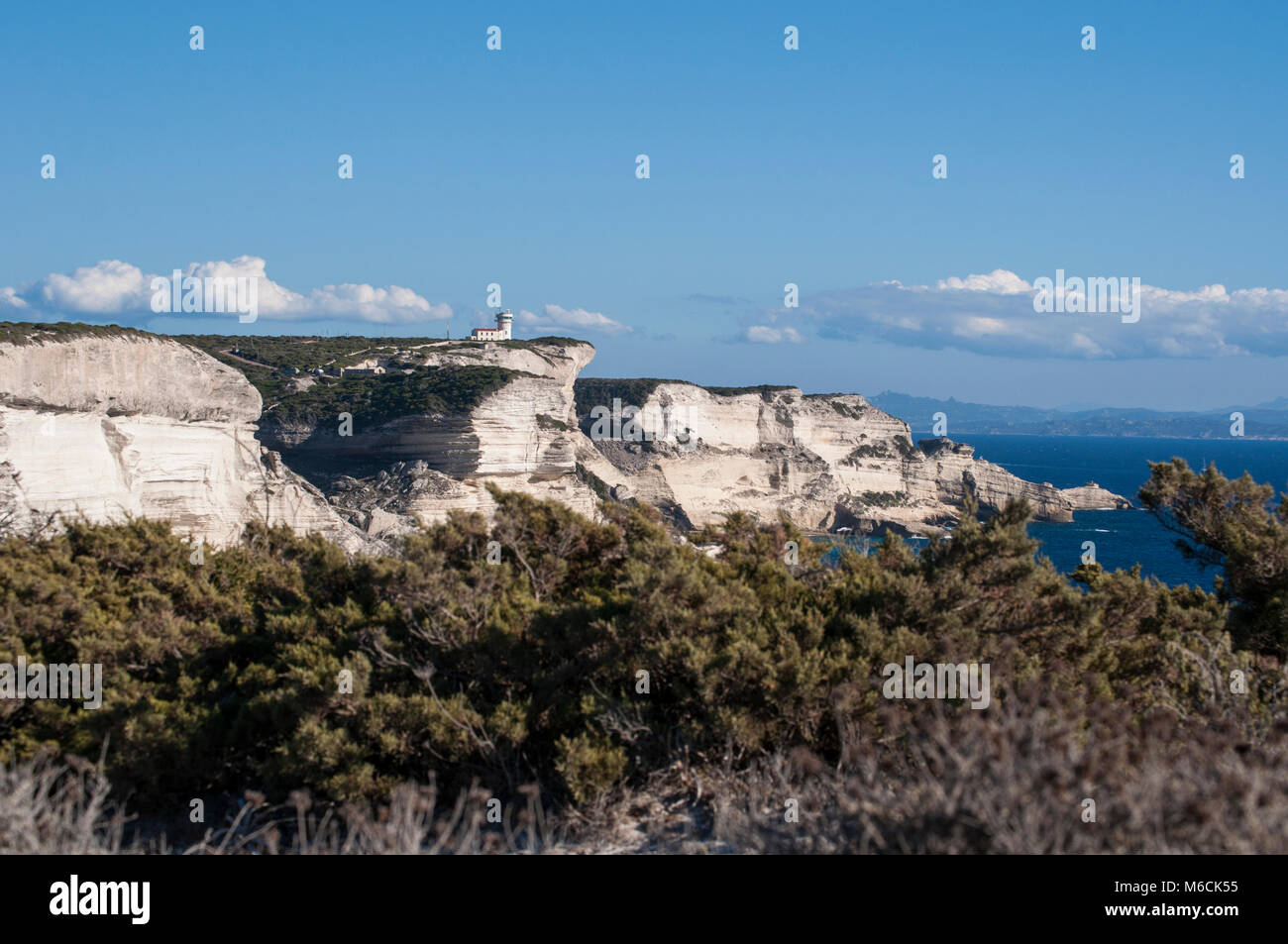 Corsica: la mozzafiato bianche scogliere calcaree nella International Bouches de Bonifacio parco marino con vista del capo Pertusato faro Foto Stock