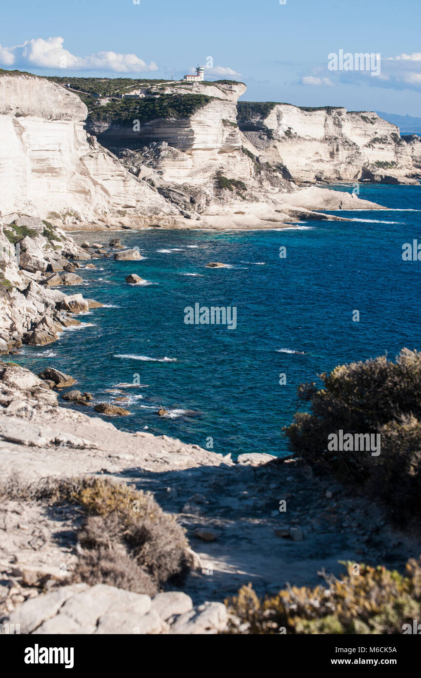 Corsica: la mozzafiato bianche scogliere calcaree nella International Bouches de Bonifacio parco marino con vista del capo Pertusato faro Foto Stock