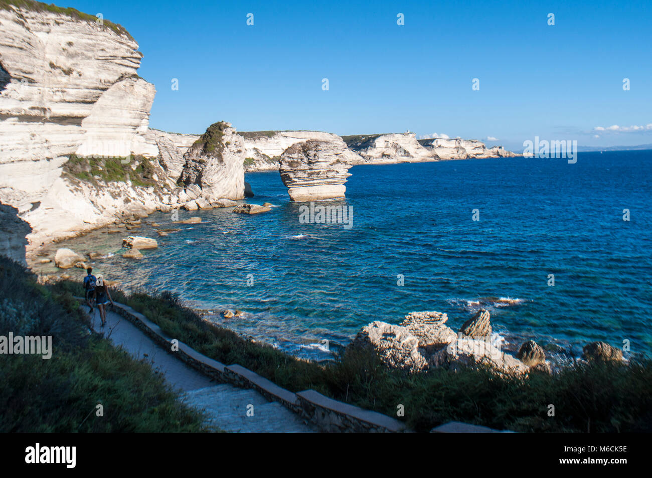 Corsica: la mozzafiato bianche scogliere calcaree nella International Bouches de Bonifacio parco marino con vista del capo Pertusato faro Foto Stock