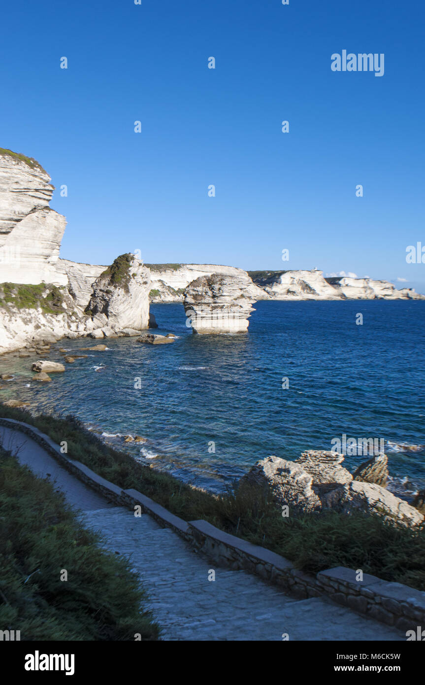 Corsica: la mozzafiato bianche scogliere calcaree nella International Bouches de Bonifacio parco marino con vista del capo Pertusato faro Foto Stock