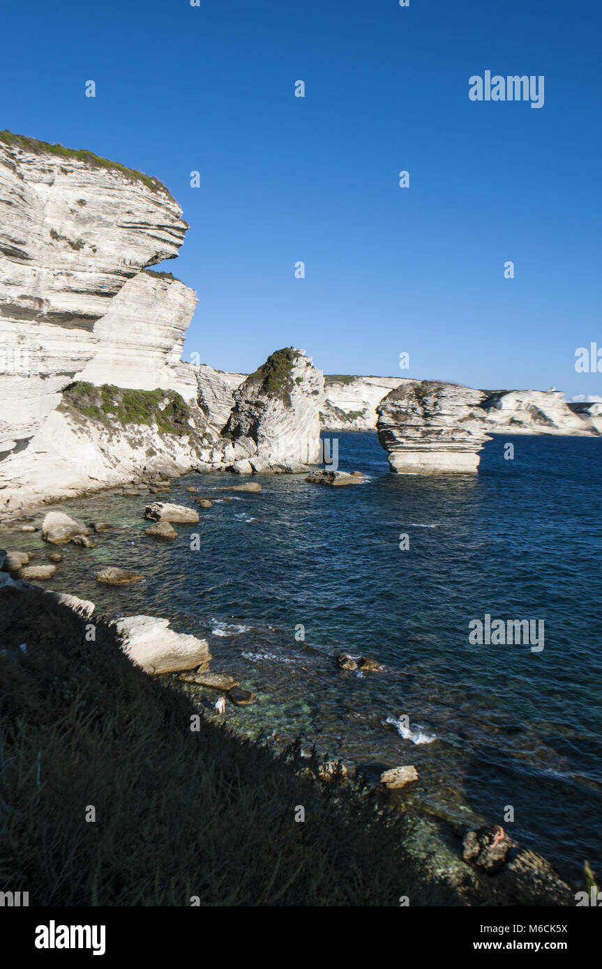 Corsica: la mozzafiato bianche scogliere calcaree nella International Bouches de Bonifacio parco marino con vista del capo Pertusato faro Foto Stock