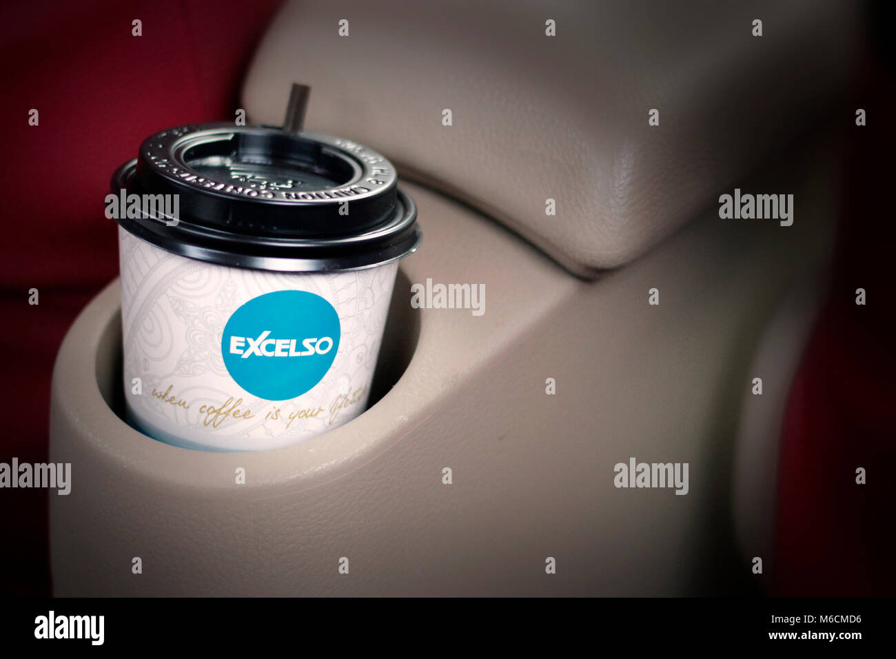 Una tazza di caffè excelso in una macchina e un rosso sedile passeggero Foto Stock
