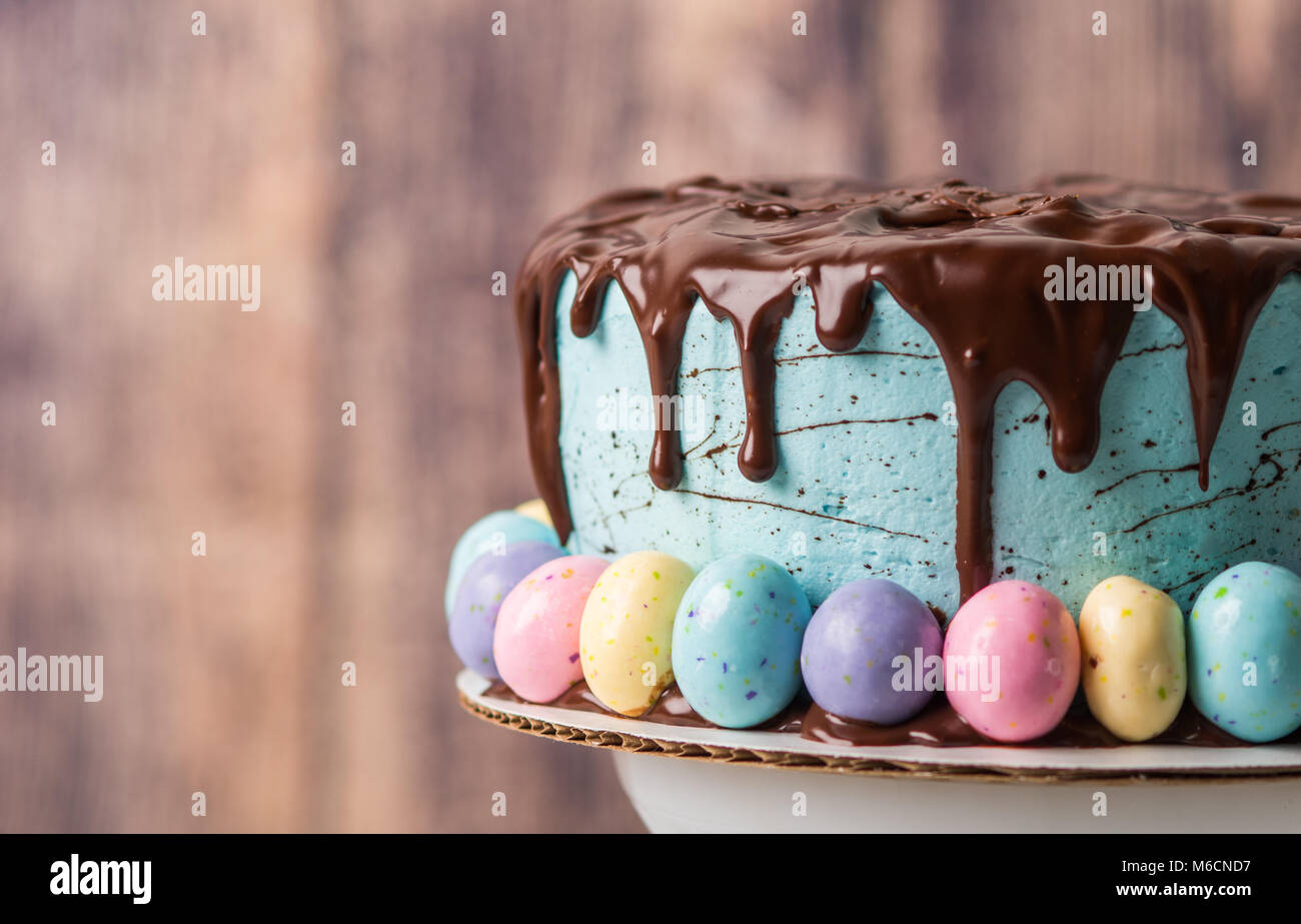 Smerigliato blu torta al cioccolato con glassa di gocciolamento e uova di Pasqua in un ambiente rustico Foto Stock