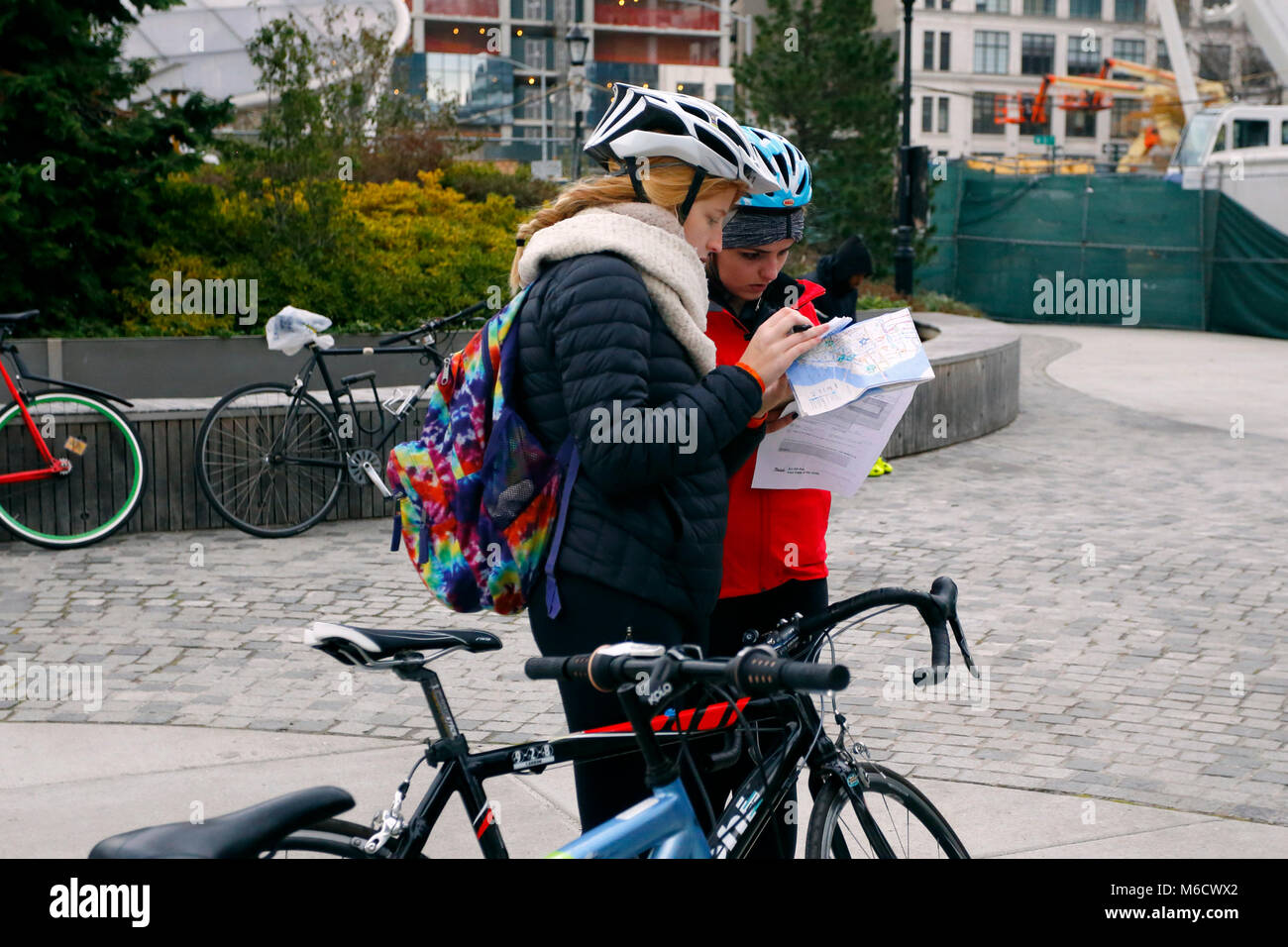 Due donne helmeted ciclisti consultare una mappa all'inizio di una carità Cranksgiving ride Foto Stock