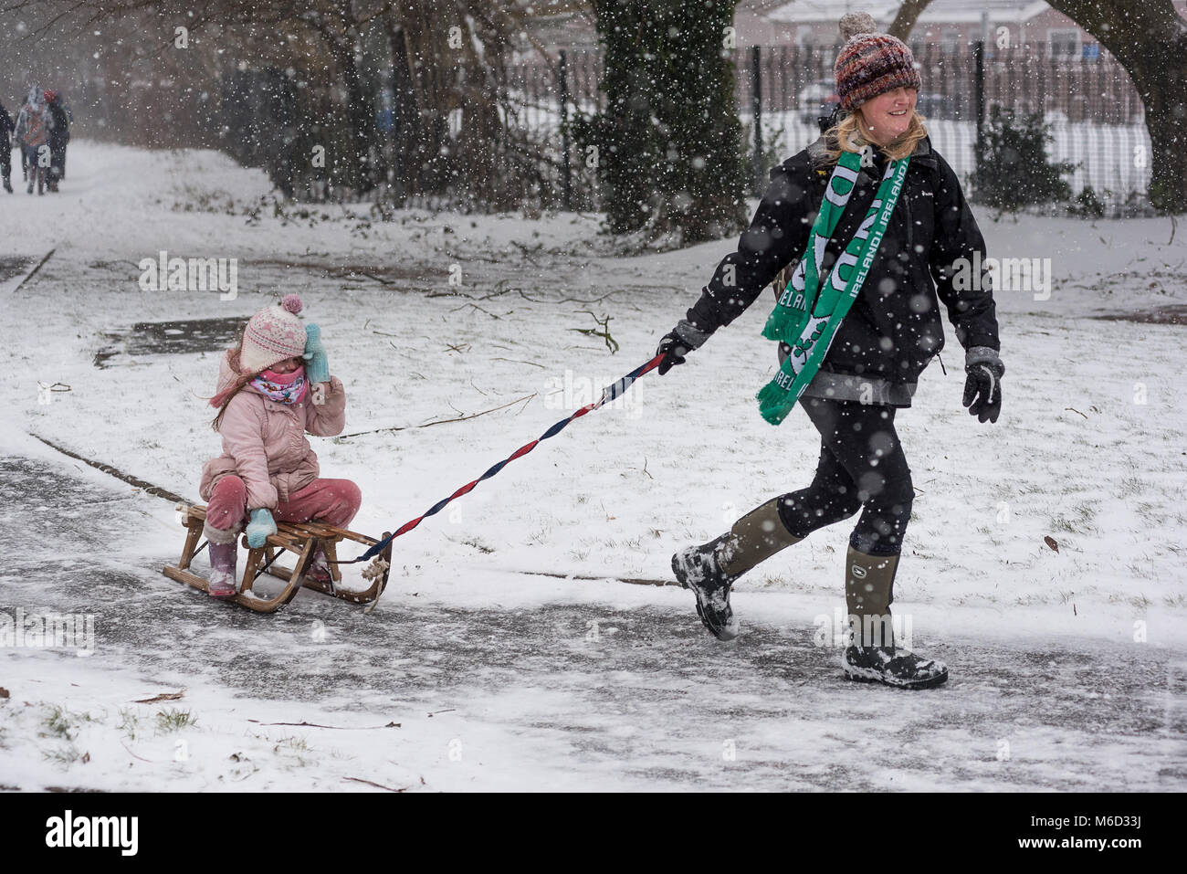 Cardiff, Galles, UK. 2 marzo 2018. Tempesta Emma: elegante il trasporto per i negozi! La mamma si trascina lungo la figlia su un tradizionale taboggan. Credito Foto: Ian HOMER/Alamy Live News Foto Stock