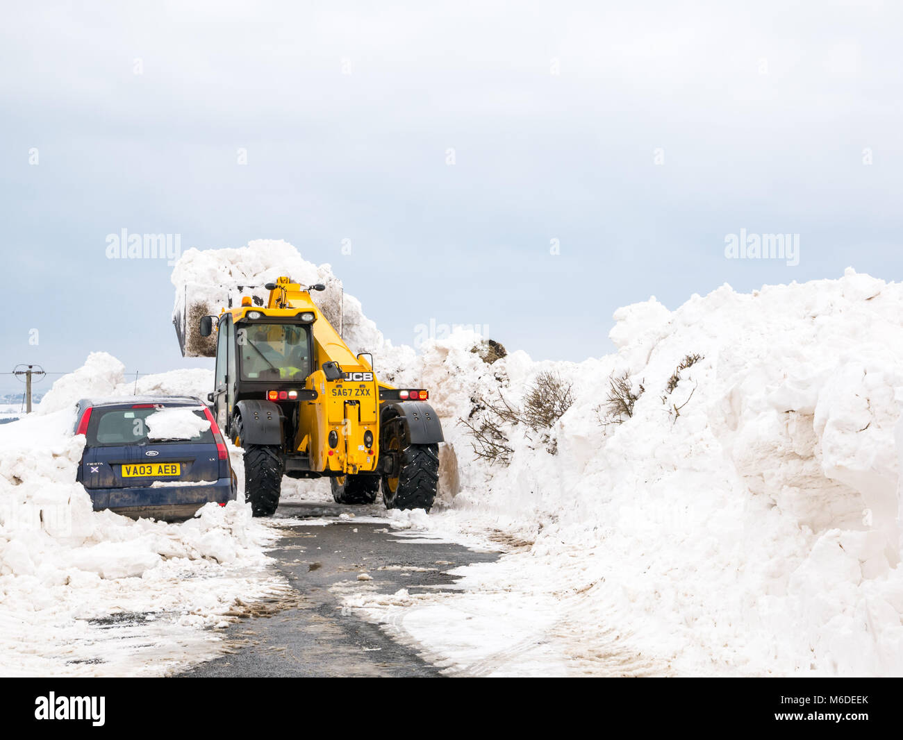 East Lothian, Scozia, Regno Unito, 3° marzo 2018. Regno Unito: Meteo la strada locale tra Drem e Haddington è chiuso da enormi derive di neve dopo la estrema arctic eventi meteo soprannominato "La Bestia da est'. Un consiglio è di scavo la cancellazione della strada. Un auto è sepolto nella neve Foto Stock