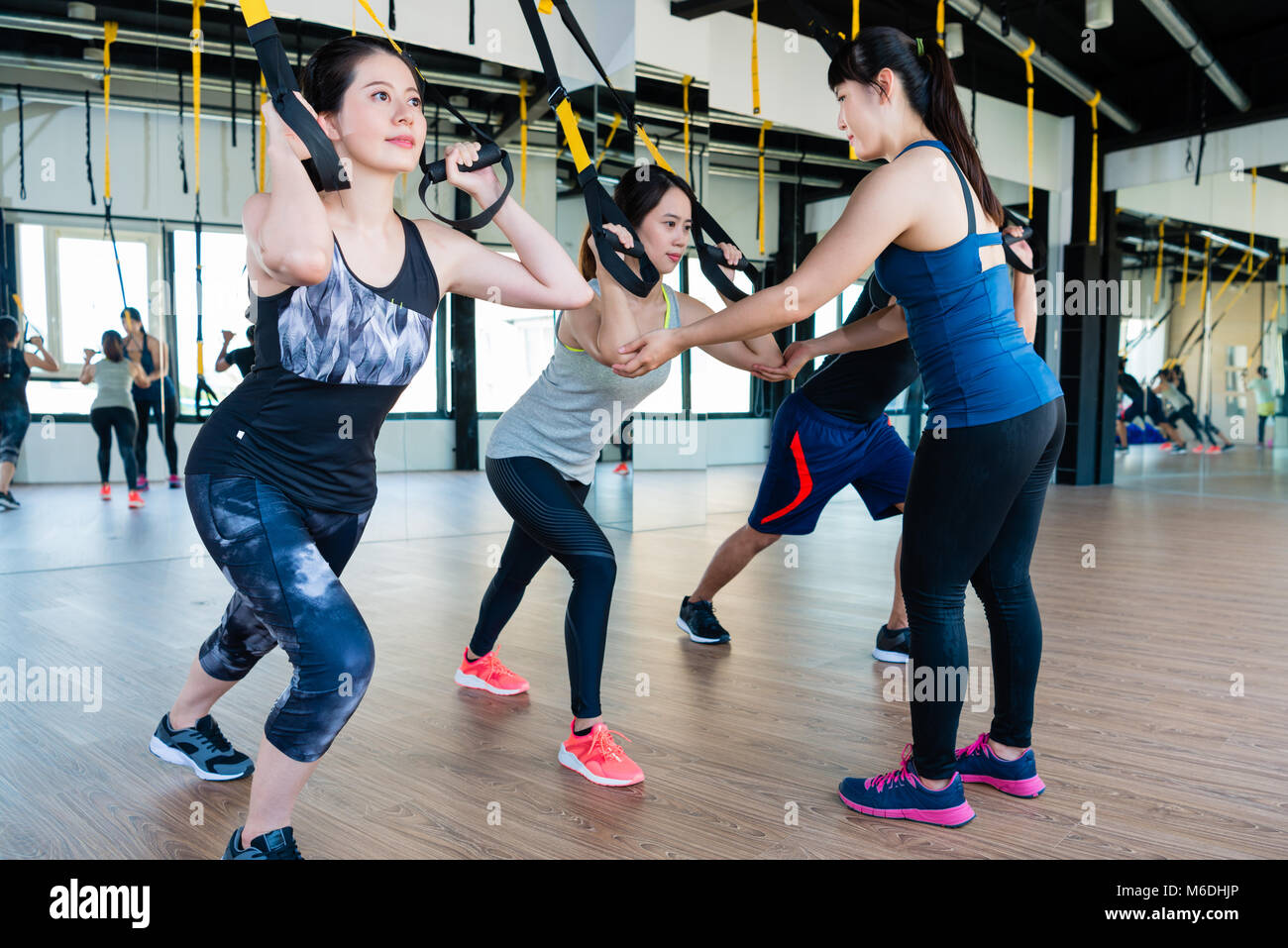 Gruppo di persone la formazione a fune elastica per corpo totale resistenza esercizio insieme con un trainer. Foto Stock
