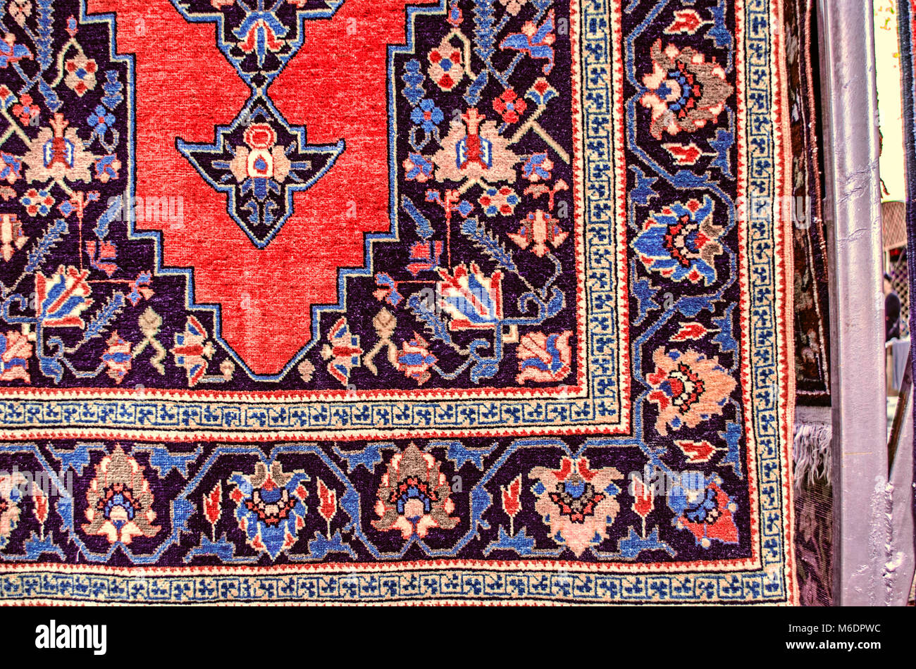 Di lana blu scuro tappeto stilizzato con motivi floreali e una cornice rossa sulla cente alla domenica gioco equo vendita di souvenir in Yerevan Foto Stock
