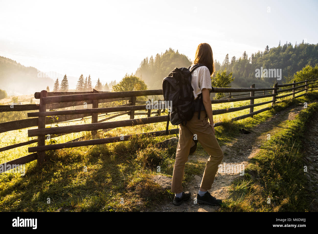 Ragazza con zaino facendo una passeggiata su per la collina e godere di uno splendido scenario di sunrise Foto Stock