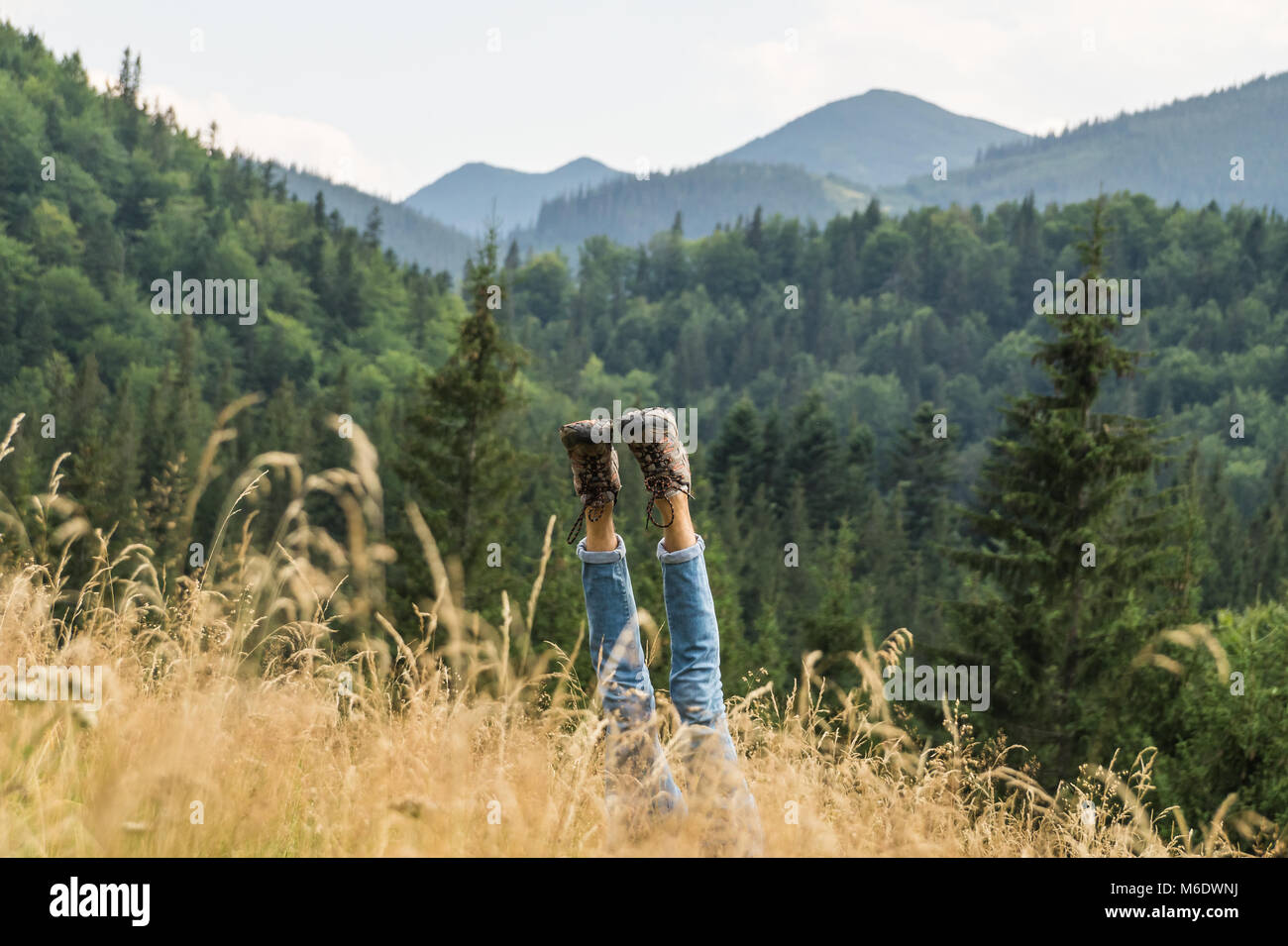 Una persona stanca rende stand a mano per ottenere il resto per gambe in scarpe da trekking su un bel prato di montagna nelle montagne dei Carpazi Foto Stock