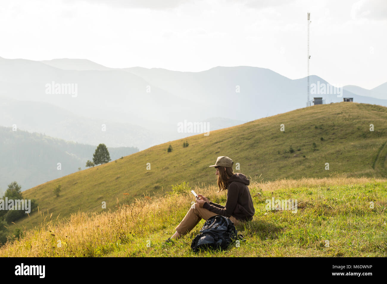Escursionista femmina portatile utilizza un tablet pc in montagne vicino Torre cellulare Foto Stock