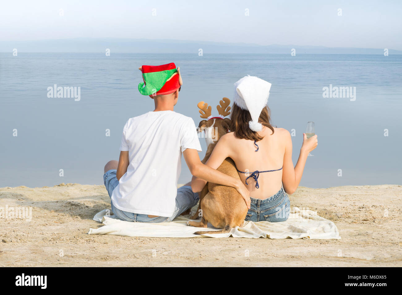 Uomo Donna e puppy in divertente nuovo anno cappelli trascorrere del tempo in mare Foto Stock