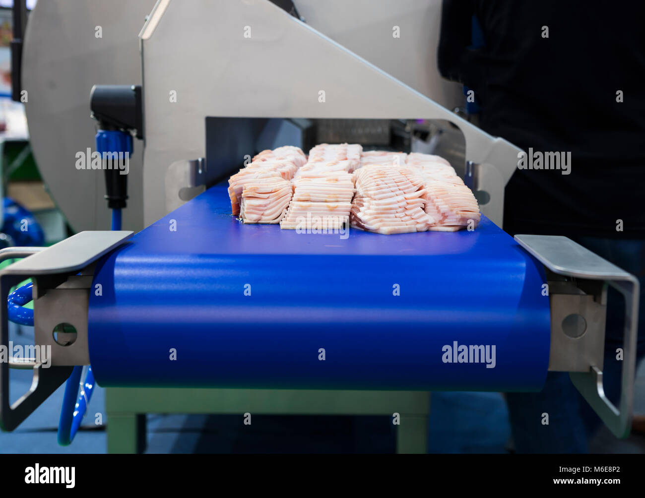 Prosciutto sul trasportatore di alimentare la macchina di taglio Foto Stock