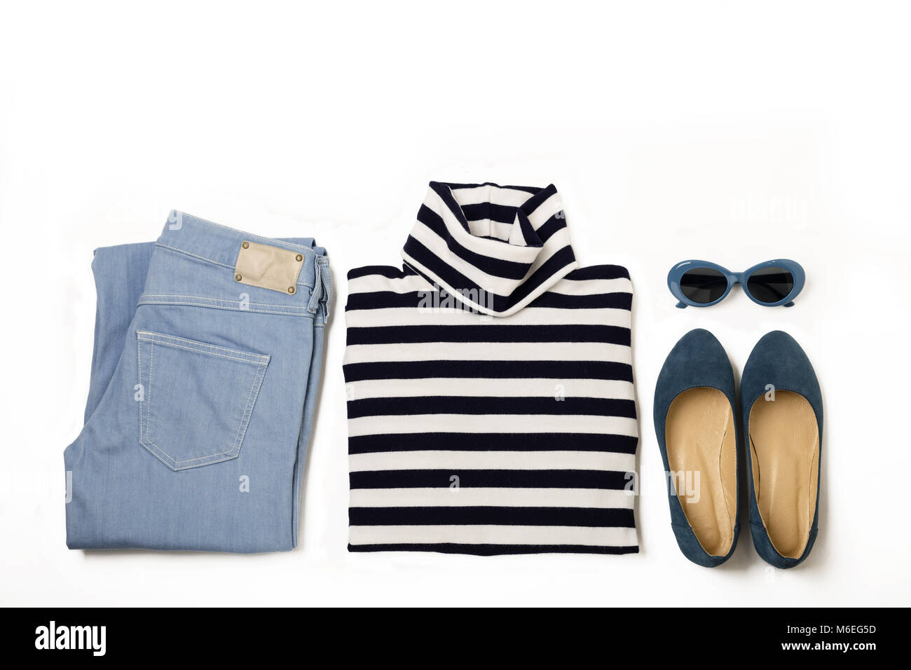 Set di moda di jeans blu, striped maglione, scarpe e sunglsses su sfondo bianco. Messa a fuoco selettiva. Foto Stock