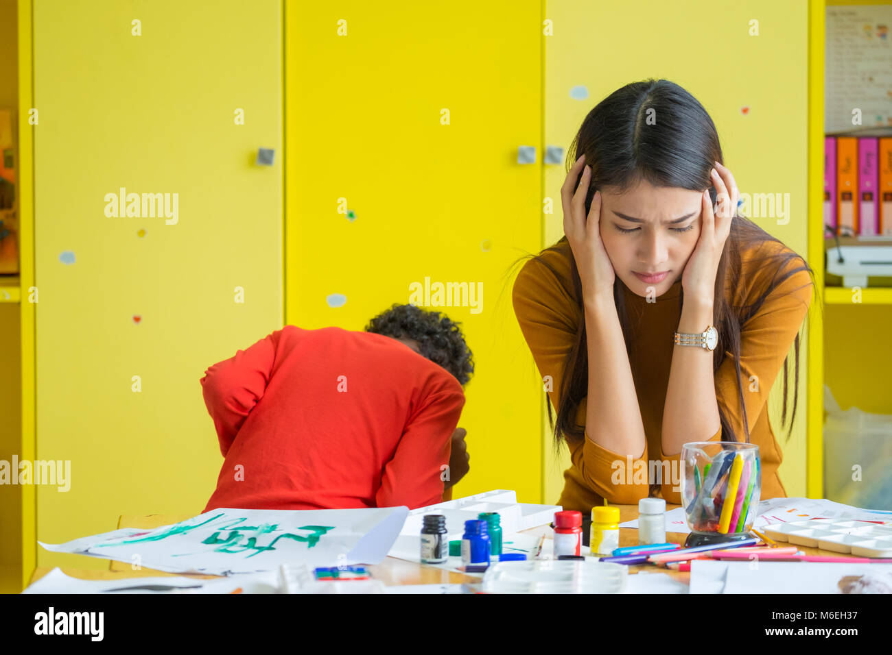 Insegnante avere mal di testa con due naughty kids in aula a scuola kindergarten Foto Stock