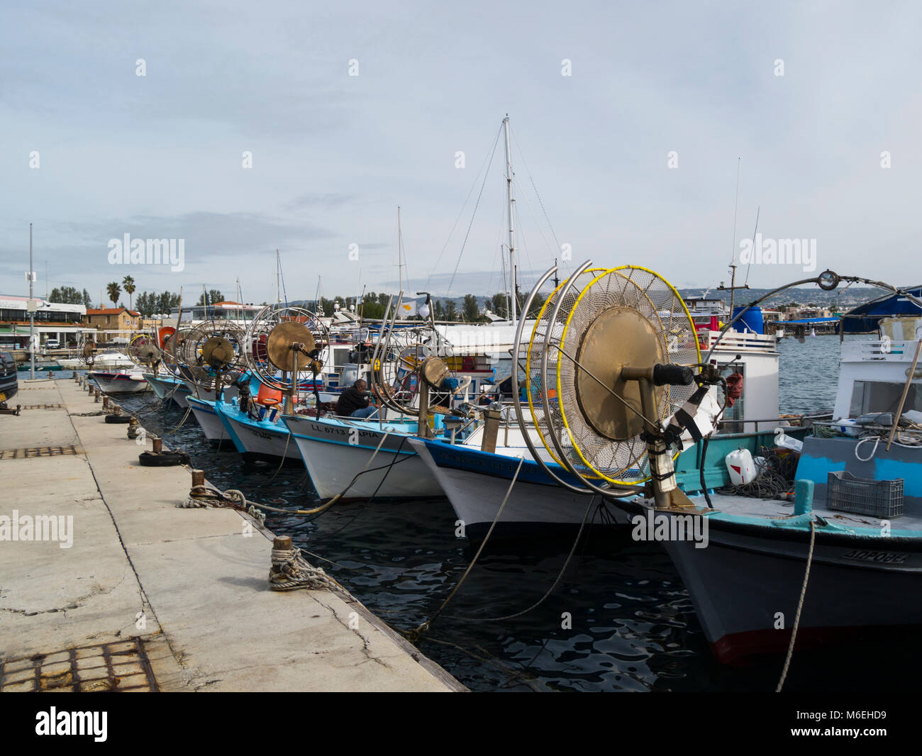 Barche da pesca ormeggiate nel vecchio porto da pesca di Kato Pafos inferiore di Pafos Paphos Cipro del Sud fisherman rammendo reti sulla sua barca nella popolare area turistica Foto Stock